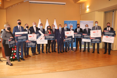zdjęcie grupowe wszystkich beneficjentów Rządowego Programu Inwestycji Lokalnych i Dróg Samorządowych trzymających tabliczki z otrzymanymi kwotami dofinansowania